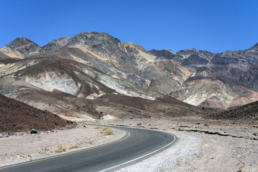 a paved, winding road in death valley national park, with mountains in the distance