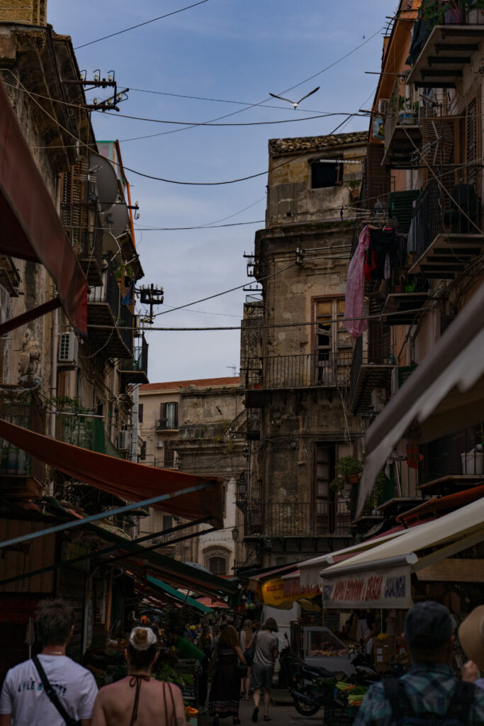 a busy street filled with people and market stands in Palermo, Italy