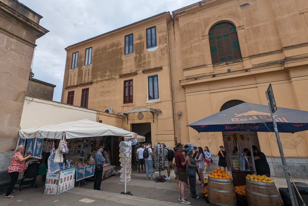 a tall yellow building with a tent in front selling souvenirs and postcards