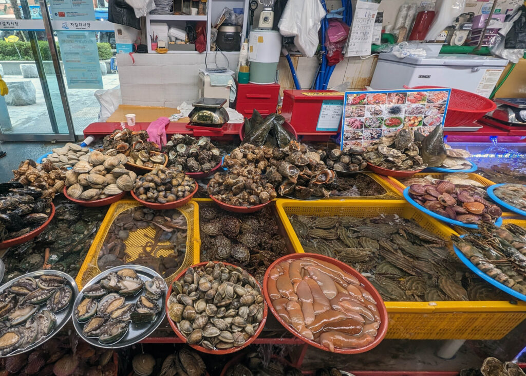 basekts and pools of different types of seafood for sale on the lower floor of jagalchi market in busan, south korea