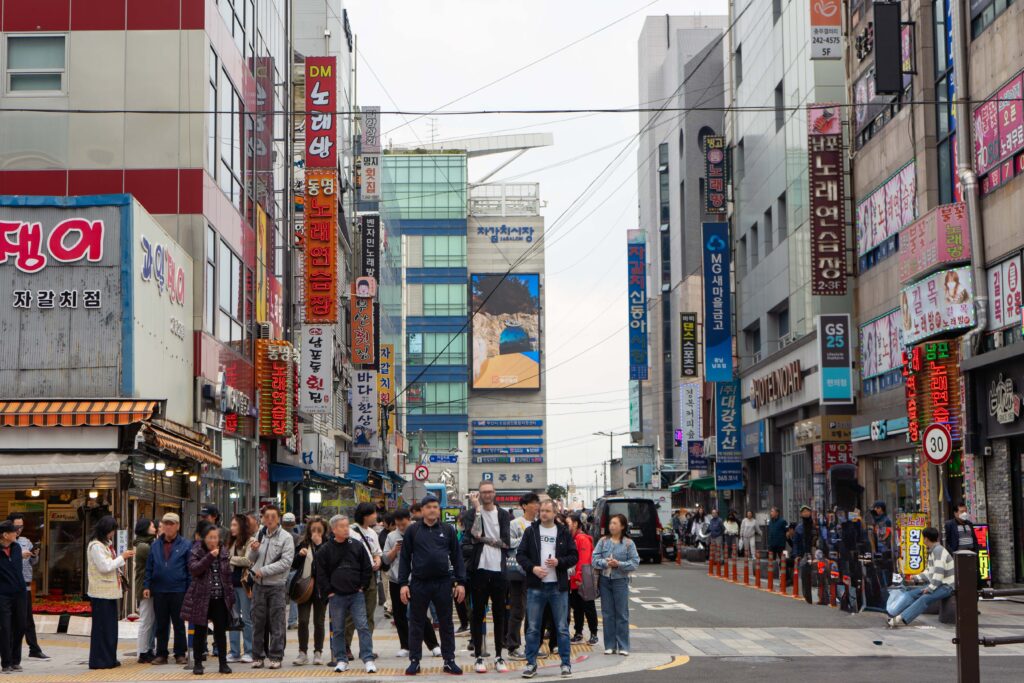 A busy city street in central Busan, with people waiting at a stoplight