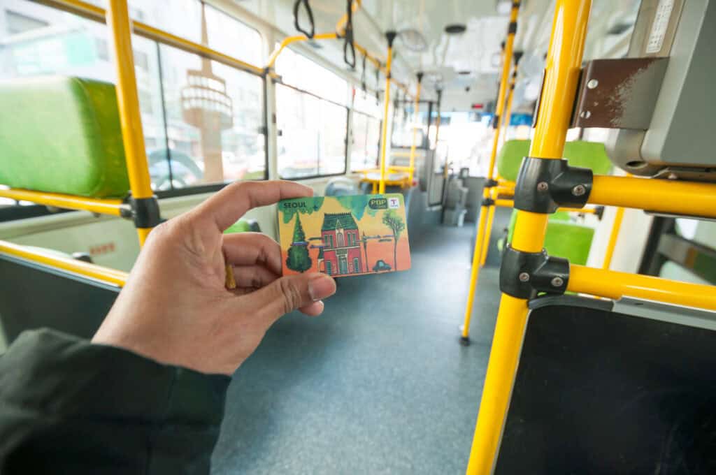 A hand holding a t-money card in Seoul South Korea, on a bus.