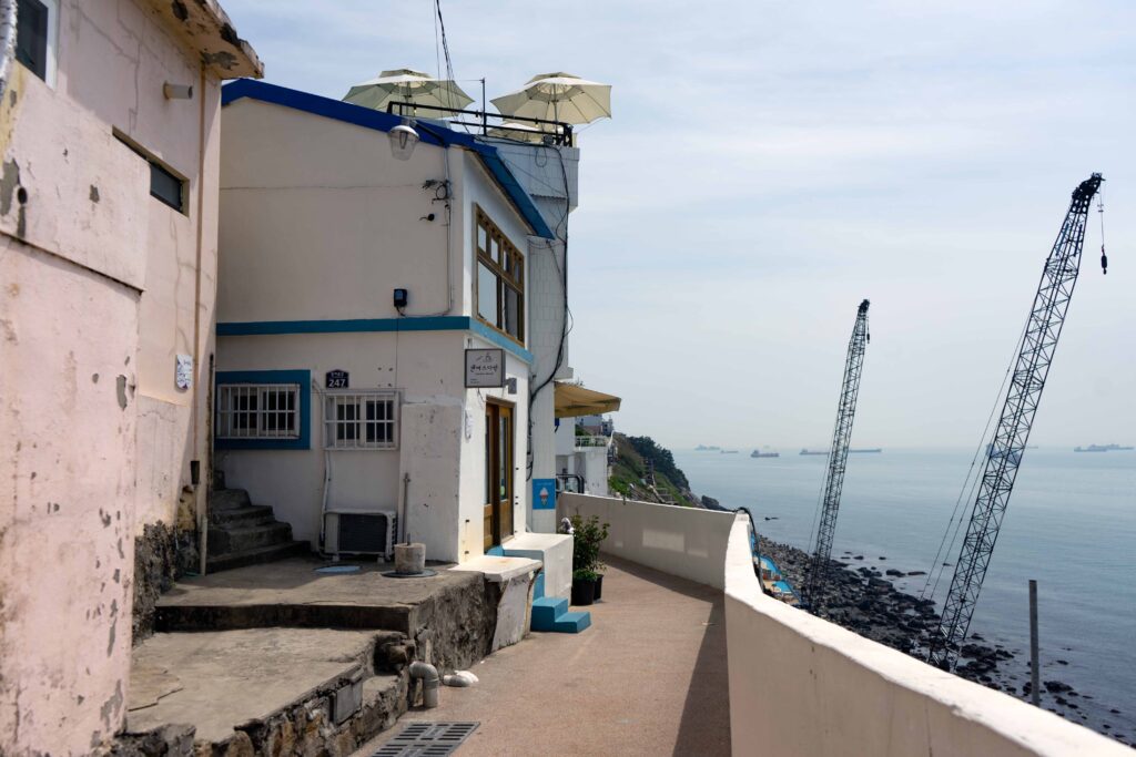 white and blue painted buildings and a view of the sea in Huinnyeoul Culture Village