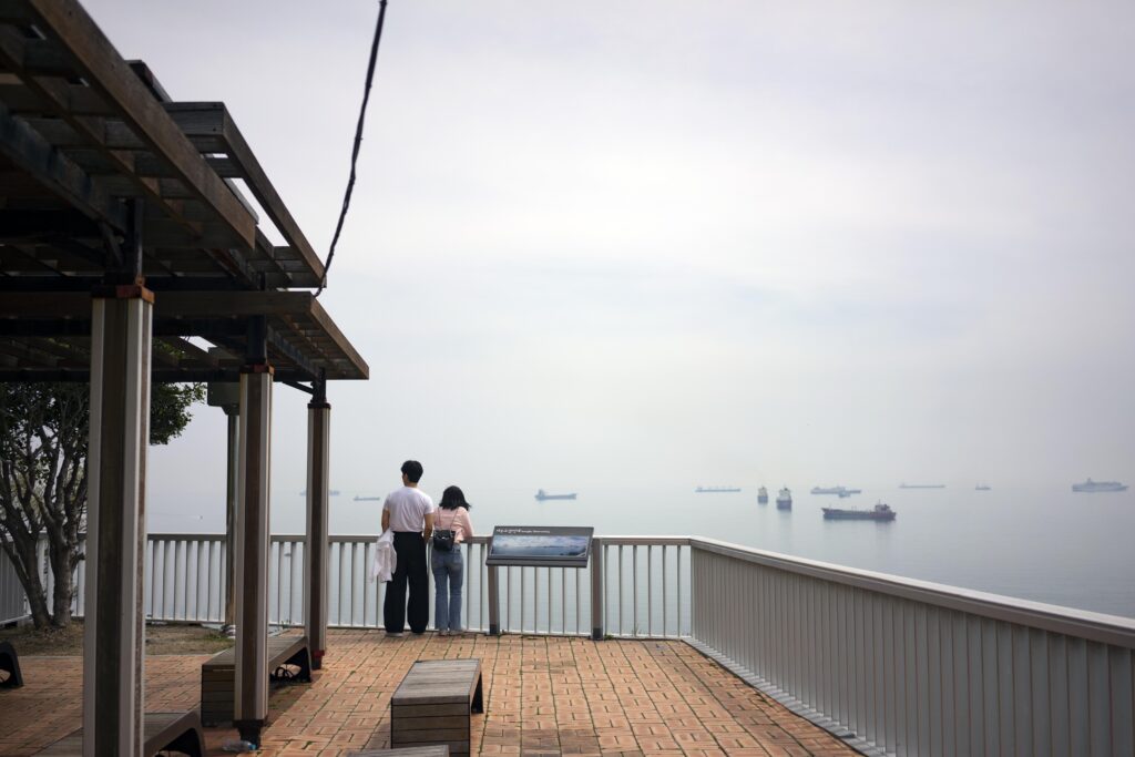 Two people standing at a railing, enjoying Coastal views from Huinnyeoul Culture Village