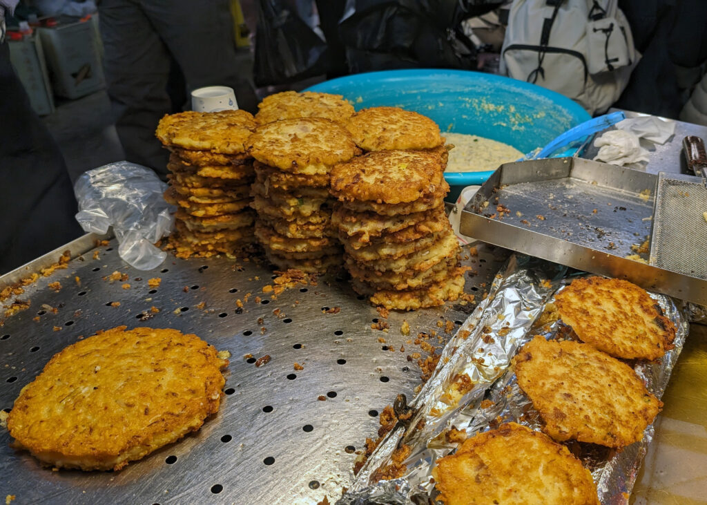 fried korean pancakes stacked on a griddle in gwanjang market, seoul