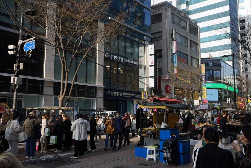 a busy street filled with shops and people in Myeongdong, Seoul