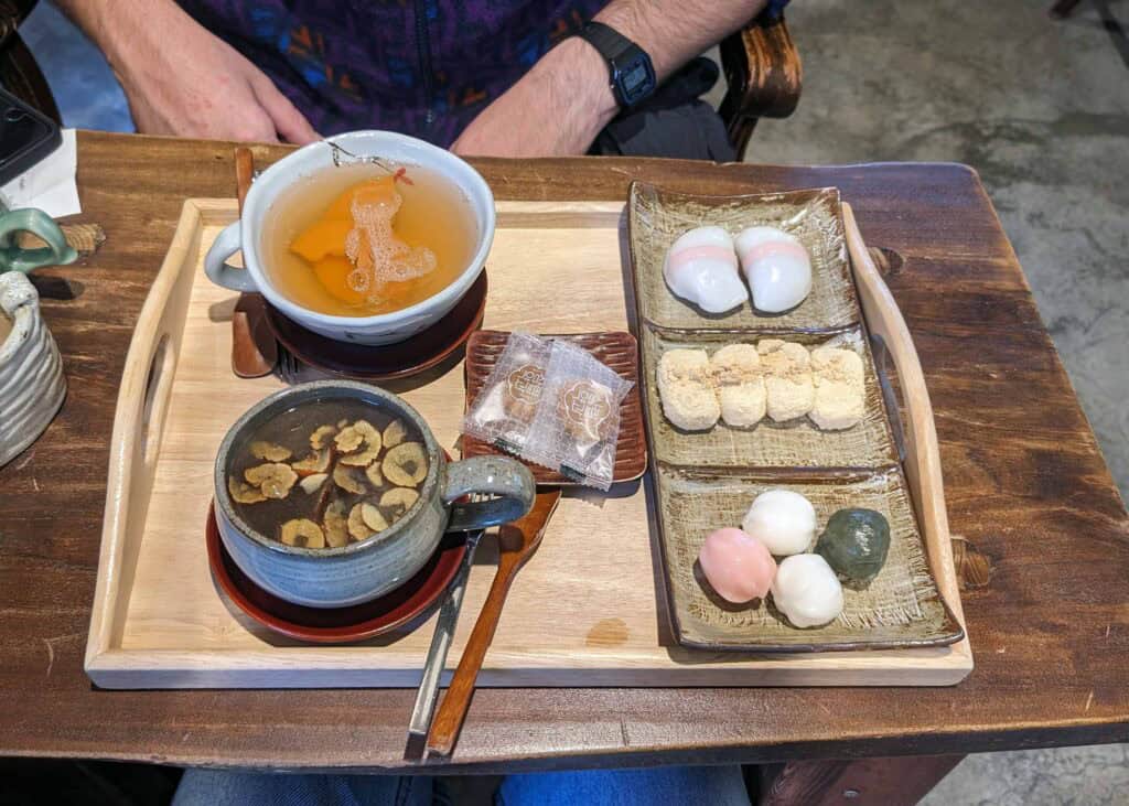 A wooden table with a tray of sweets and two cups of tea on it, at Sinyet Chatjip in Seoul.