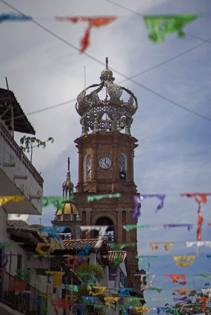 a church steeple against a blue sky with colourful flags flying in the foreground