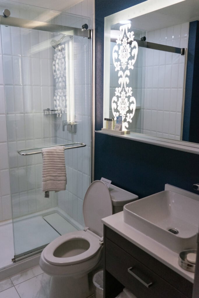 a toilet and sink next to a shower with glass siding at the champlain waterfront hotel