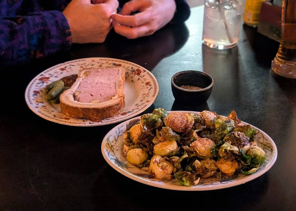 a plate of brussel sprouts next to a plate of Pâté en Croûte at Hog & Penny