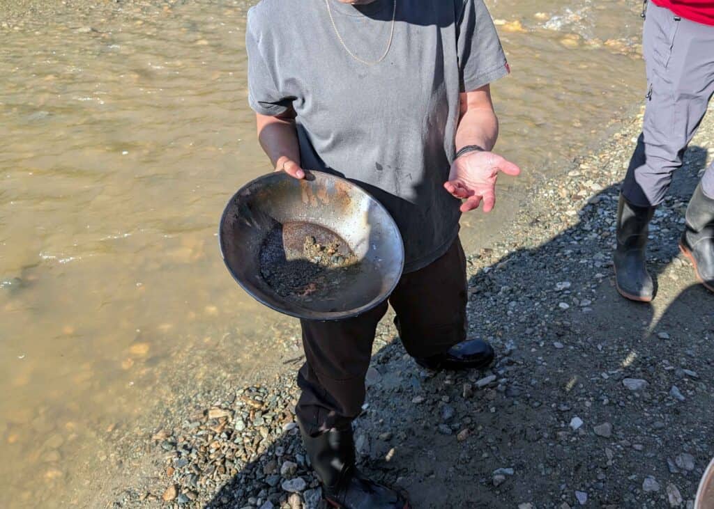 a person wearing a grey shirt and black pants holding a black gold pan, describing what is in the pan