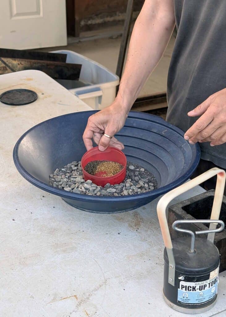a large gold pan with hands showing a small dish of gold flakes
