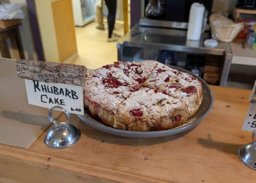 A plate of rhubarb cake resting on a wooden counter with a sign reading "rhubarb cake."