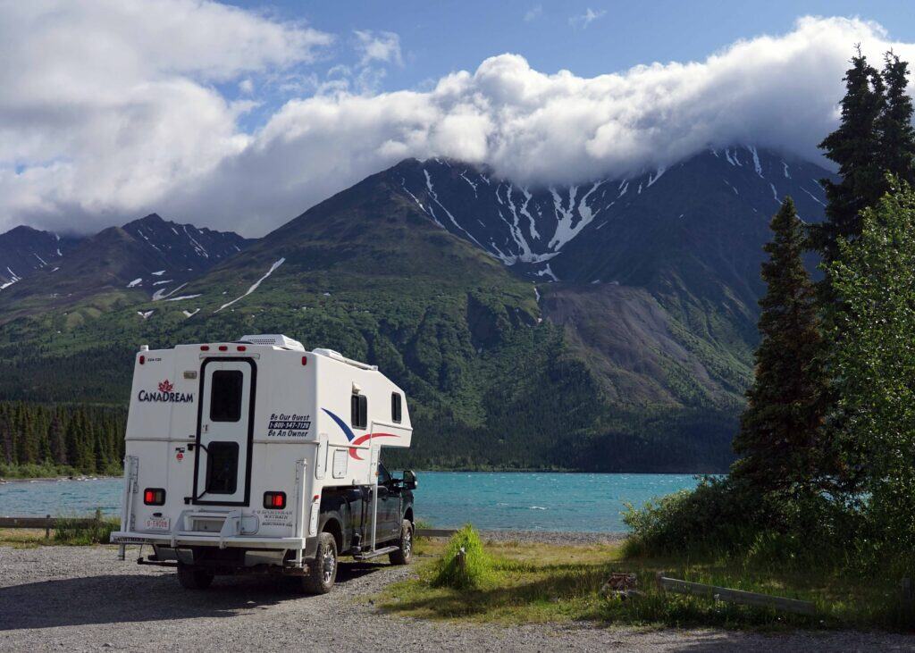 A CanaDream RV camper parked next to a turquoise blue lake.