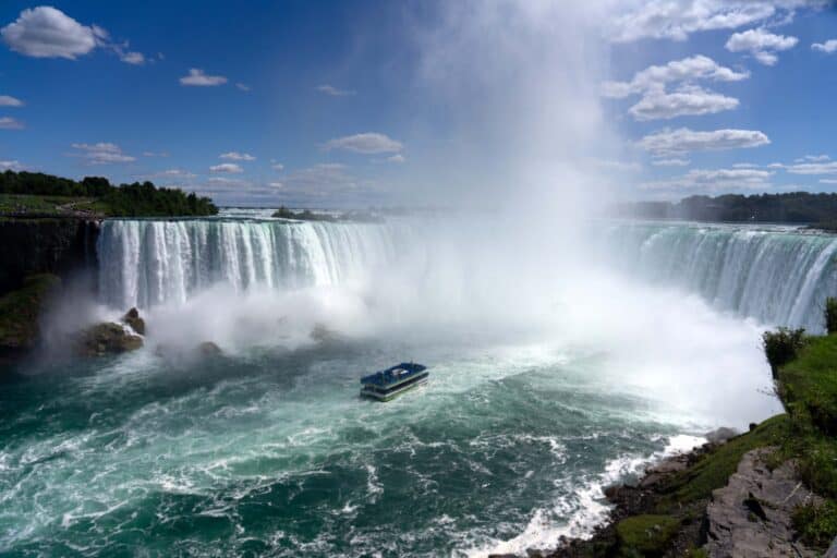 A boat heading toward the Horseshoe Falls on a sunny day at Niagara Falls.