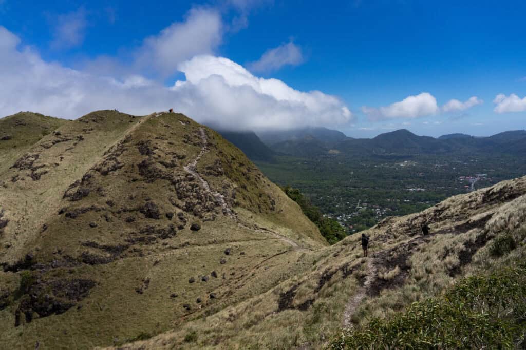 Hikers walking along La India Dormida ridge overlooking El Valle de Antón crater and surrounding mountains.