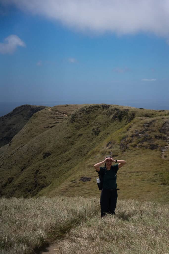 Blonde woman standing on the ridge of a volcano, La India Dormida hike summit.