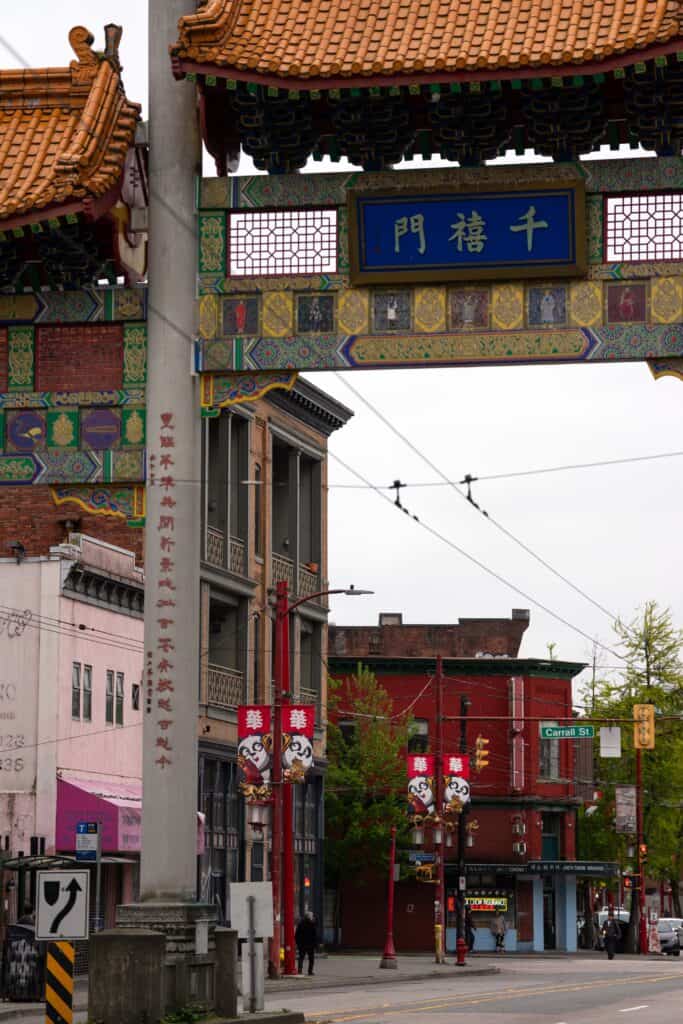 The ornate Millennium Gate marks the entrance to Vancouver’s Chinatown, framed by historic buildings and red street banners.