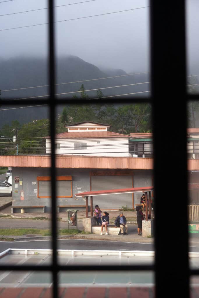 View of El Valle de Anton, Panama, through a window frame with mountains and local buildings in the distance.