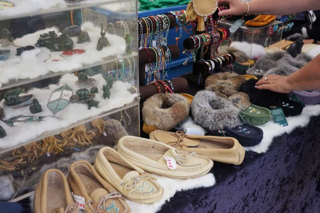 A table with traditional moccasins and jewelry displayed on it.