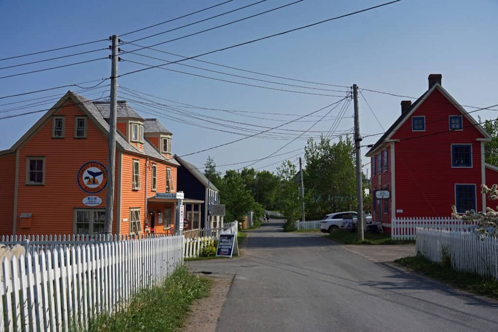 Colourful historic buildings and white picket fences along a quiet street in Trinity, Newfoundland.