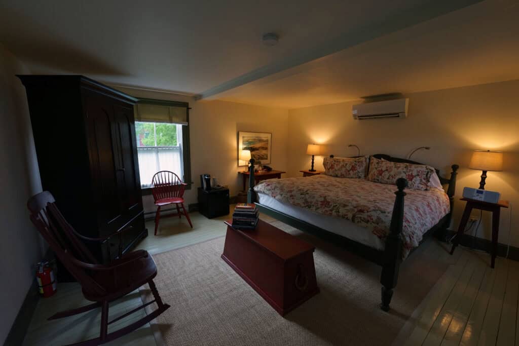 Spacious guest room at Fisher's Loft Inn in Port Rexton, featuring a king bed, heritage-inspired furnishings, and a cozy seating area.