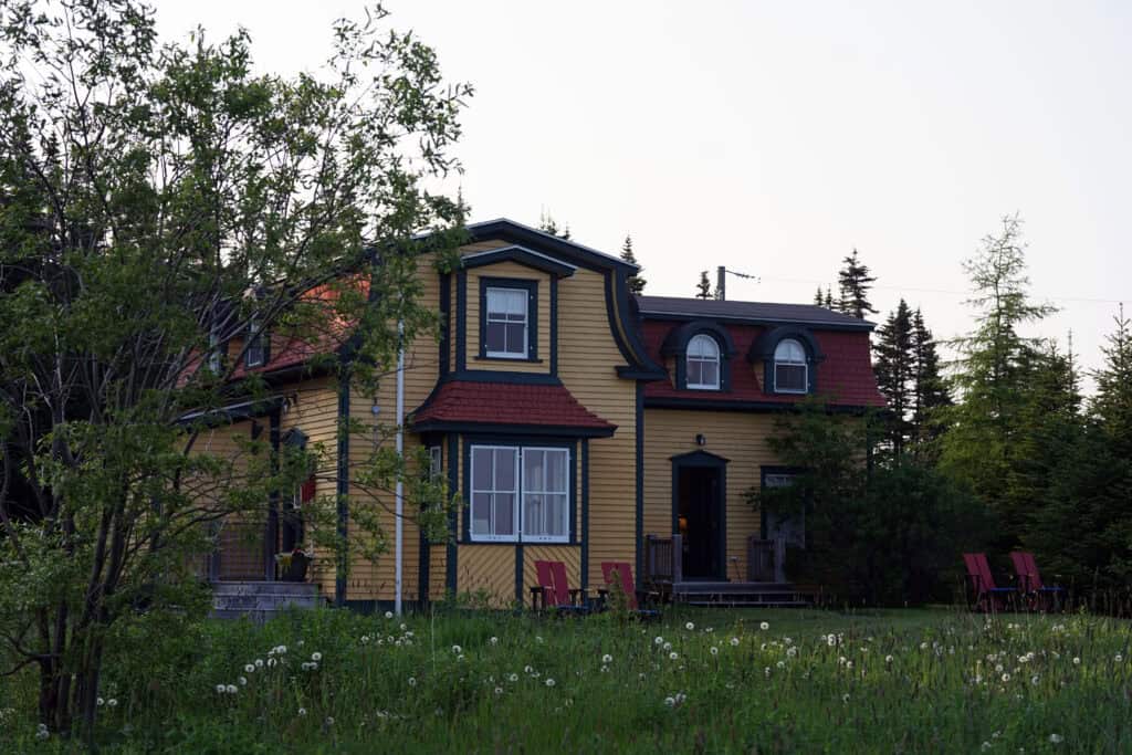 One of the heritage-inspired guest buildings at Fisher's Loft Inn in Port Rexton, surrounded by wildflowers and overlooking Trinity Bay.