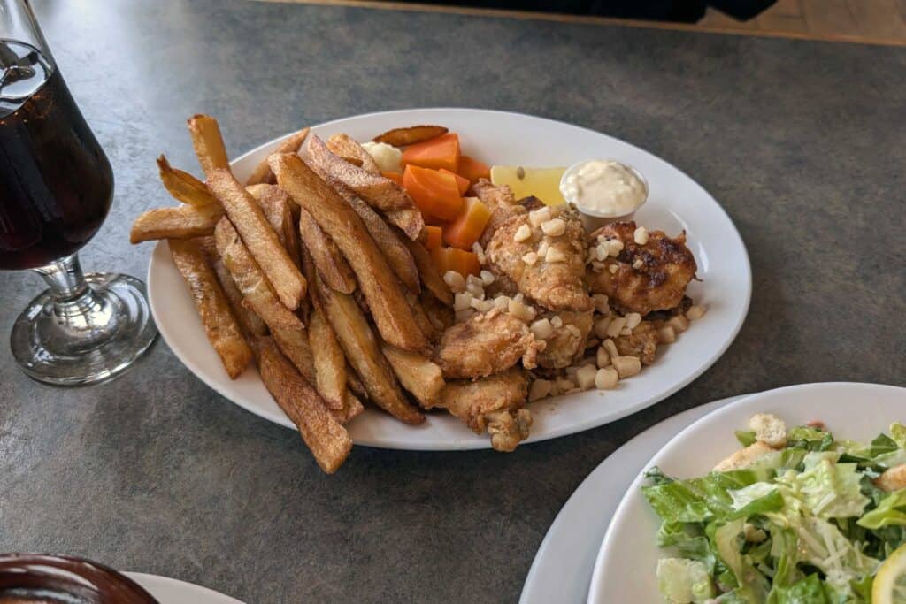 Plate of traditional Newfoundland cod tongues served with hand-cut fries, vegetables, tartar sauce, and lemon at Dock Marina Restaurant in Trinity.