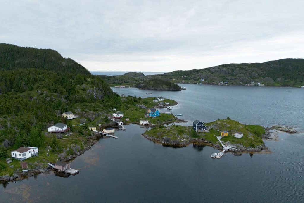 An aerial view of the Exploits Islands, showing a small fishing outport with traditional, colourful homes, in a bay.