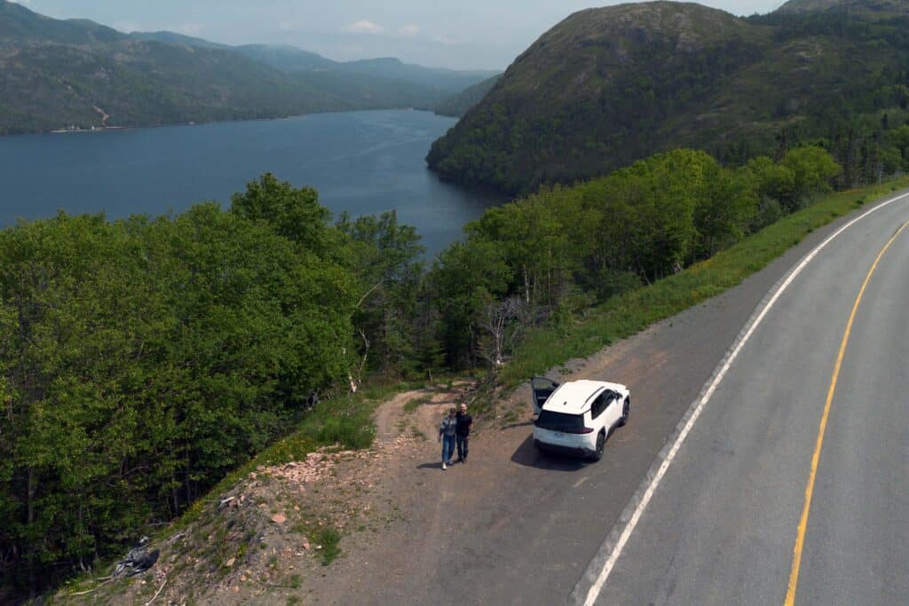 Viewpoint along Highway 360 overlooking Bay d'Espoir fjord on Newfoundland's south coast, with a parked vehicle and steep forested hills surrounding the water.