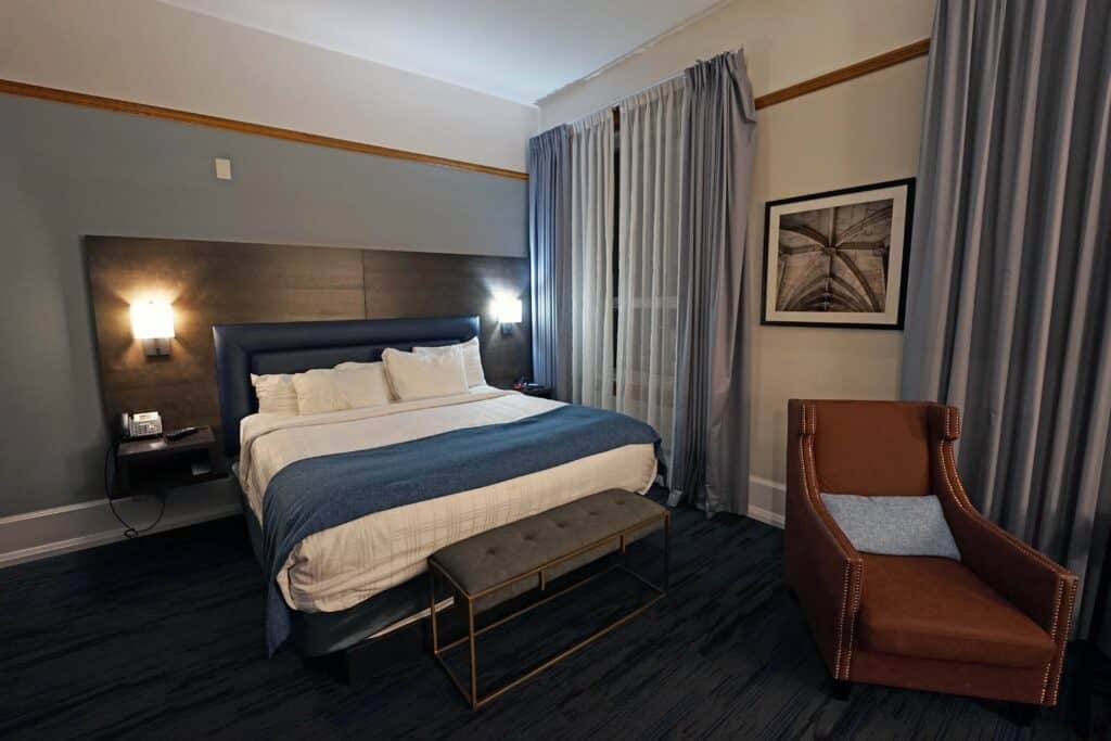 Guest room at The Courthouse Hotel in Thunder Bay with a king bed, high ceilings, large windows and seating area.