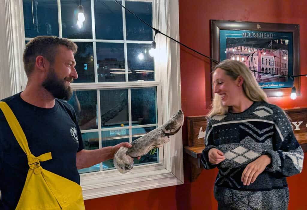 A woman taking part in a traditional Newfoundland Screech-In ceremony, preparing to kiss a cod held by the ceremony host at the Newfoundland Embassy Pub in St. John’s.