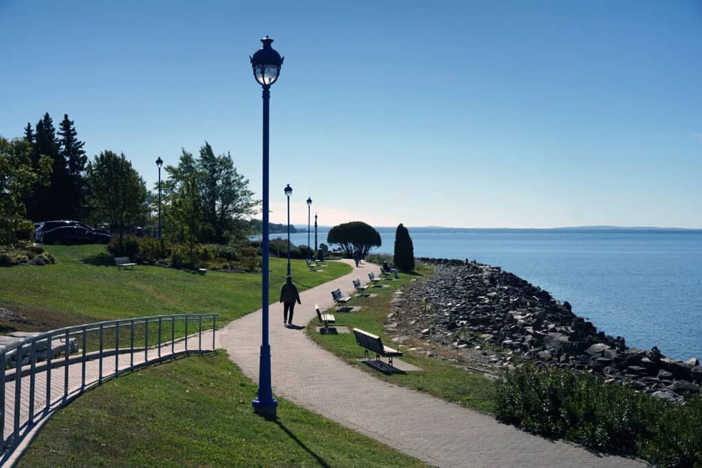Paved waterfront path with benches and lamp posts along the shore of Lake Nipissing in North Bay in fall.