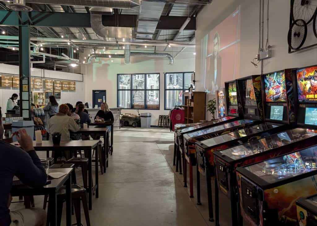 Interior of Gateway City Brewery in North Bay, with customers seated at tables and a row of pinball machines.